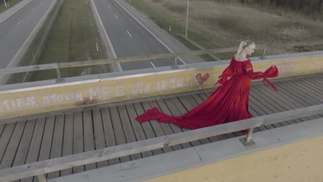 A-dramatic-drone-shot-spin-of-a-model-with-beautiful-dress-on-a-bridge-posing