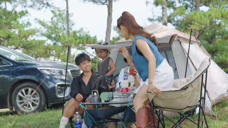 Un-Grupo-De-Personas-Tomando-Café-Juntas-Durante-Un-Viaje-De-Campamento,-Sentadas-Frente-A-Su-Tienda-Rodeadas-De-Un-Paisaje-Impresionante