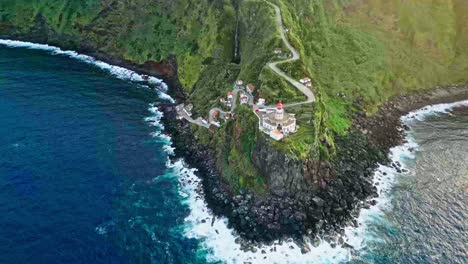 Farol-do-Arnel-lighthouse-and-green-seaside-hill-in-the-Azores,-wide-aerial-pan
