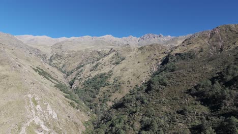 Fly-over-hills-and-mountains-near-the-waterfall-"Los-Alisos"-in-Tafí-del-Valle,-Tucuman,-Argentina-on-a-sunny-clear-sky-day