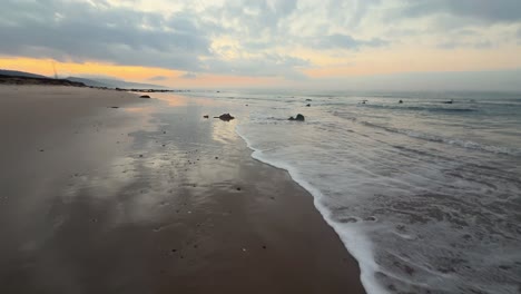 Sea-waves-gently-splash-onto-the-sandy-shores-of-coastal-Spain-in-the-evening,-capturing-the-tranquility-and-beauty-of-the-seaside