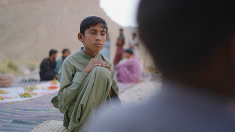 A-young-boy-sitting-in-Pakistan-Balochistan-talking-to-his-friends-and-smiling-with-traditional-dress