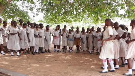 African-black-female-young-student-performing-tribal-indigenous-ritual-dance-in-remote-rural-village-wearing-school-uniform