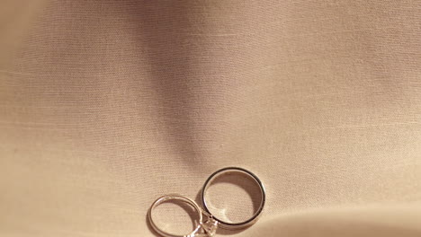 Dropping-a-pair-of-engagement-rings-made-of-platinum-and-diamonds-on-a-cloth-laid-on-a-table