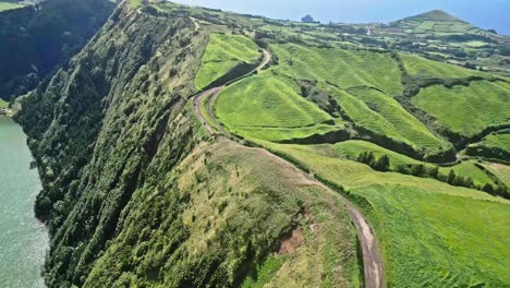 Green-rolling-hills-and-winding-dirt-road-in-a-lush-countryside-landscape