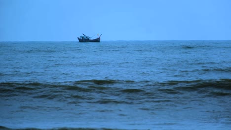 Lonely-fishing-boat-in-the-Indian-ocean,-waves-breaking-on-coast,-blue-hour