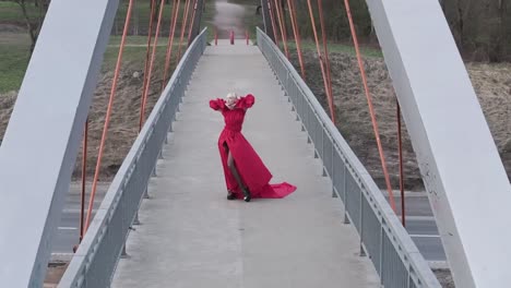 Langsam-Bewegte-Luftdrohnenaufnahme-Eines-Wunderschönen-Models-In-Modischem-Kleid-Auf-Einer-Brücke
