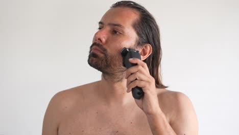 A-man-is-using-electric-shaver-to-trim-mustache-and-beard-while-standing-in-front-of-mirror-in-bathroom-at-home,-shave