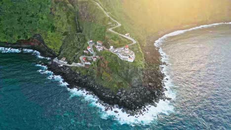 Wide-aerial-pan-of-Farol-do-Arnel-lighthouse-on-seaside-hill-at-Azores