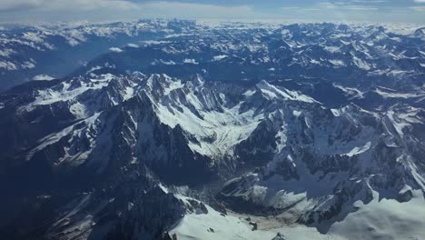Elevated-aerial-view-of-an-Alpine-Glacial-in-The-Alps-Range,-shot-from-a-jet-cockpit-flying-over-it-at-8000m-high