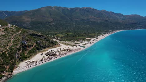 Borsh-Beach-with-White-Pebbles-and-a-Green-Background-of-Olive-Trees-on-the-Albanian-Riviera,-Top-Summer-Destination