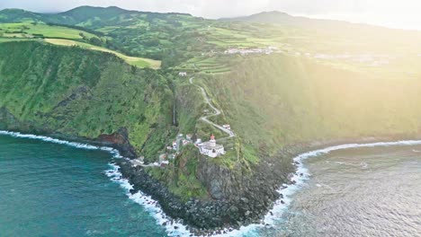 Farol-do-Arnel-lighthouse-on-seaside-Azores-cliff,-wide-aerial-pull-out
