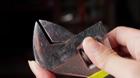 Fingers-with-long-nails-open-a-metal-pliers-loosening-the-nut-closeup-shot-tools-English-key-wrench