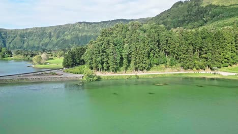 Beautiful-lake-surrounded-by-lush-green-forest-and-mountains-under-a-bright-sky