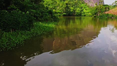 Antena-Baja-A-Lo-Largo-De-La-Orilla-Verde-De-Un-Hermoso-Lago-Ubicado-En-Abuja,-La-Capital-De-Nigeria,-áfrica