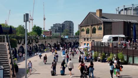 Bustling-scene-at-Kings-Cross,-London-with-people-exploring-Coal-Drops-Yard-on-a-sunny-day