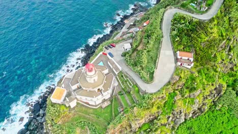 Scenic-aerial-view-of-a-lighthouse-on-a-cliffside-by-the-ocean