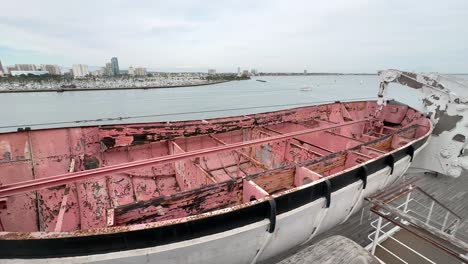 Viejo,-Oxidado,-Histórico-Bote-Salvavidas-En-El-Queen-Mary-Con-Vistas-A-La-Ciudad-De-Long-Beach,-California