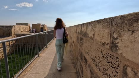 A-person-walks-along-the-ancient-walls-of-the-Citadel-in-Gozo,-Malta,-embracing-the-historical-significance-and-panoramic-views-of-this-fortified-landmark