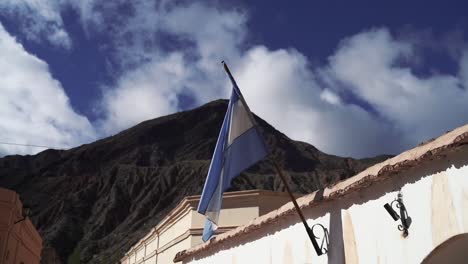 Eine-Argentinische-Flagge,-Die-Stolz-Auf-Einem-Haus-In-Der-Gegend-Mit-Bergen-Im-Hintergrund-Weht-Und-Nationalstolz-Und-Kulturelles-Erbe-Symbolisiert