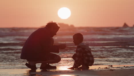 Uncle-and-nephew-bonds-on-beach-collecting-shells-during-golden-hour-sunset