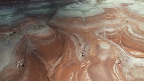 Aerial-View-of-Lonely-Woman-Walking-Uphill-in-Moonlike-Desert-Landscape-of-Utah-USA,-Drone-Shot