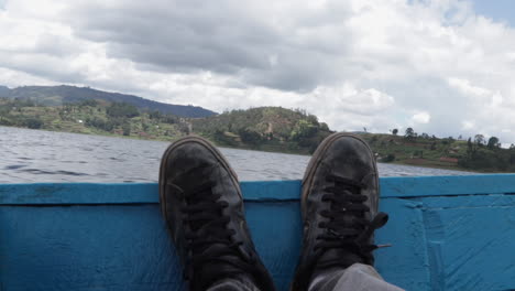 Feet-of-a-person-resting-while-taking-motor-boat-in-Uganda,-POV