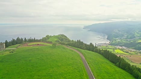 Stunning-aerial-view-of-Miraduros-Ponta-da-Madrugada-in-Portugal-with-lush-green-hills-and-ocean