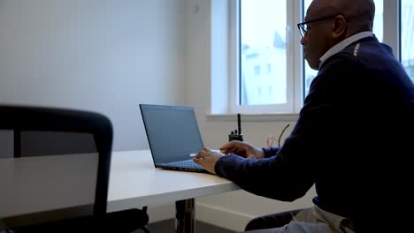 Man-working-on-laptop-in-bright-office-setting,-focused-and-productive