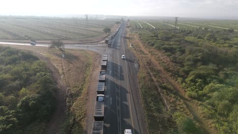 Filmischer-Drohnenabflug-Auf-Eine-Große-Anzahl-Von-Lastwagen,-Die-In-Einer-Langen-Schlange-Auf-Einer-Autobahn-Vor-Einem-Grenzposten-Feststecken