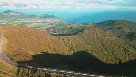 Furnas,-azores,-portugal,-showcasing-lush-hills-and-a-coastal-road,-aerial-view