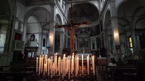 Dentro-De-La-Iglesia-De-La-Basílica-Del-Crucifijo-De-San-Giovanni-Crisostomo-En-Venecia,-Italia,-Hay-Una-Estatua-De-Jesús-En-El-Crucifijo-Con-Velas-Encendidas-Delante,-Que-Simboliza-La-Devoción-Y-La-Espiritualidad.