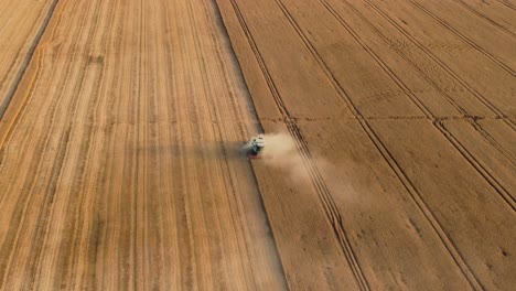 Combine-harvester-harvesting-cereals-on-a-sunny-summer-day,-aerial-rising-shot