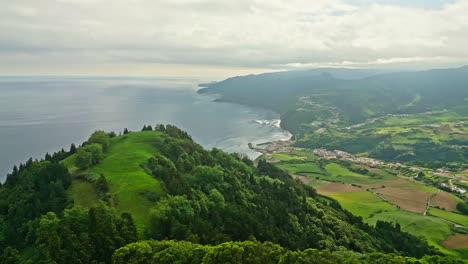 Lush-green-hills-and-a-coastal-town-meet-the-Atlantic-Ocean-in-the-Azores,-Portugal