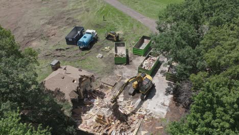 Drone-shot-of-machines-destroying-a-wooden-house-during-sunny-day
