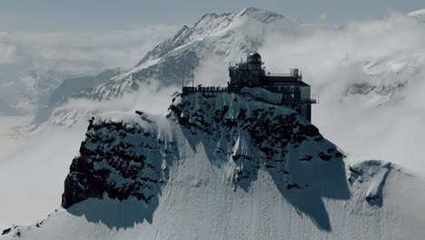 Slow-Circling-Shot-of-Jungfraujoch-with-Clouds-Rolling-Over-Peaks