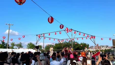 Die-Menge-Genießt-Das-Lebhafte-Japanische-Festival-Unter-Sonnigem-Himmel-Mit-Laternen-Und-Traditionellen-Aufführungen