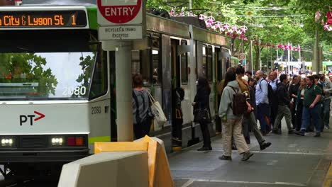 Tram-arrived-at-the-stop-with-daily-commuters-disembarking-and-boarding-the-tram-during-rush-hour-in-Melbourne-city's-bustling-Central-Business-District,-influx-in-population