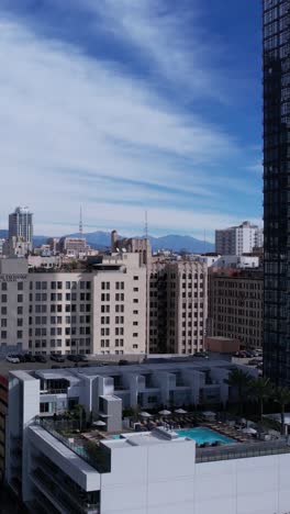 Vertical-Drone-Shot,-Downtown-Los-Angeles-Buildings,-Rooftop-Parking-and-Swimming-Pool,-California-USA