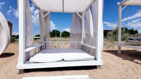 Relajarse-En-Una-Cama-De-Playa-Dentro-De-Un-Mirador-Blanco-Con-Cortinas-Transparentes-En-Un-Hermoso-Día-De-Verano