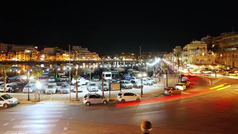 Timelapse-of-the-illuminated-Marsaskala-Bay-as-the-town-centre-on-a-summer-night-with-people-hanging-outside-on-the-promenade-in-Malta