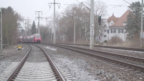 Red-Deutsche-Bahn-train-speeds-on-track-on-a-cloudy-day,-close-up