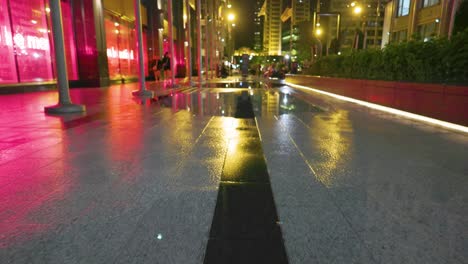 Low-Angle-Ansicht-Von-Chicago-In-Der-Nacht-Nach-Regenfällen,-Der-Nasse-Bürgersteig-Reflektiert-Das-Licht-Von-Gebäuden-Straßenlaternen