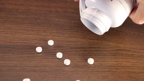 White-pills-falling-from-plastic-jar,-symbol-of-drug-or-supplement-overdose