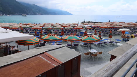 Colorful-umbrellas-line-the-beach-in-Monterosso-al-Mare,-Cinque-Terre-on-a-sunny-day