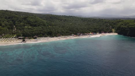 Vista-Aérea-De-La-Playa-Virgen-En-Karangasem,-Bali,-Indonesia,-Que-Muestra-Su-Costa-Prístina,-Su-Exuberante-Vegetación-Y-Sus-Vibrantes-Aguas-Turquesas,-Perfecta-Para-Viajes-Tropicales-Y-Escenas-De-Naturaleza.