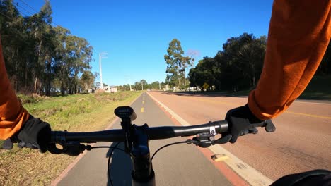 Cyclist-cycling-on-a-bike-path-shared-with-a-highway-with-car-traffic,-FPV-hyperlapse