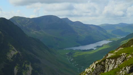 Clouds-racing-above-mountaintop-of-High-Stile-as-shadows-rapidly-move-across-side-of-Fleetwith-Pike,-valley-and-lake-Buttermere
