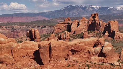 Impresionante-Vista-De-Formaciones-Rocosas-Rojas-En-Moab,-Utah,-Con-Montañas-Cubiertas-De-Nieve-Al-Fondo