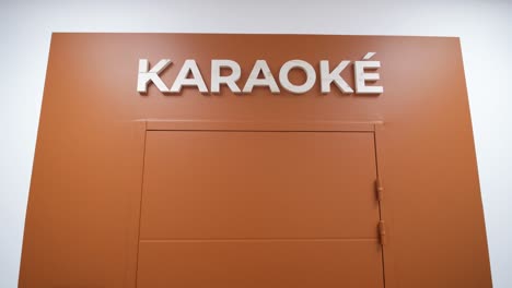 Orangefarbener-Karaoke-Raum-Eingang-Mit-Auffälliger-Beschilderung-In-Minimalistischem-Design